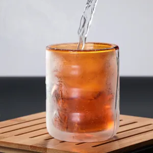 Vista detallada de taza de vidrio de doble pared con diseño en espiral y borde ámbar.