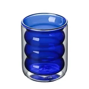 Taza de vidrio de doble pared con un diseño ondulado azul, ideal para café y jugos.