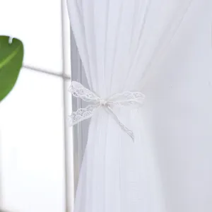 White sheer curtain detail with delicate lace tie, elegant home decor fabric for living room.
