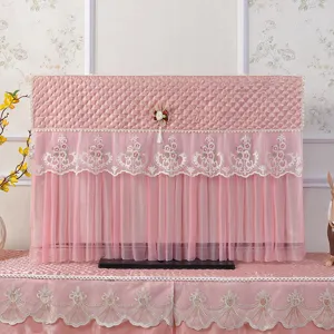 Dettaglio copertura antipolvere TV in pizzo trapuntato rosa con ricami floreali e frange.
