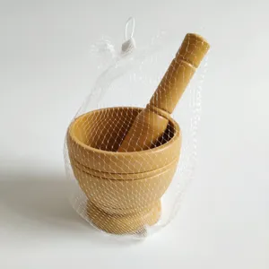 Wooden manual garlic mortar and pestle detail view with mesh packaging, kitchen tool.