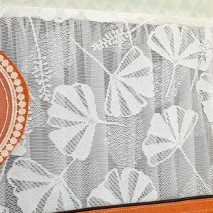 Detalle de tela de encaje blanco para cubierta de refrigerador con patrón de hojas de ginkgo.