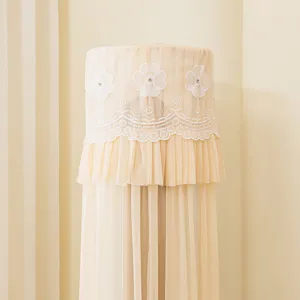 Vista detallada de la funda de aire acondicionado cilíndrica beige con delicado bordado.