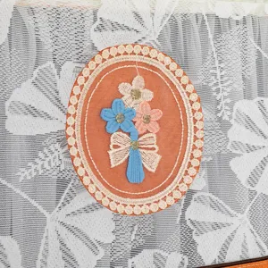 Vista detallada de funda antipolvo para frigorífico con parche floral bordado y lazo.