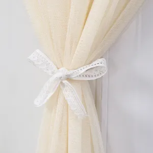 Dettaglio in primo piano della copertura beige in rete con fiocco in pizzo bianco.