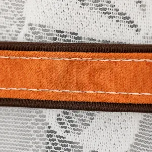 Primer plano detallado de la funda para frigorífico con encaje blanco y borde naranja.