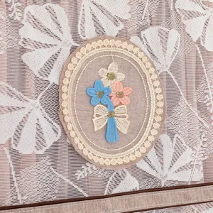 Detalle de funda antipolvo de tela con exquisito bordado floral y encaje delicado.