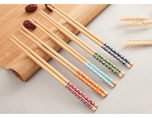 Primo piano di bacchette in legno in stile giapponese con motivi floreali e stuoia di bambù.