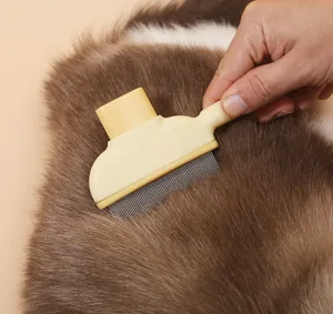 Detail shot of a pet slicker brush gently grooming a cat's soft fur, showing metal pins.
