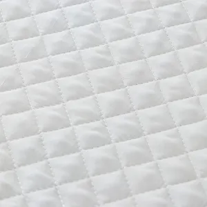 Primer plano de la textura de tela acolchada blanca con costuras de diamantes.