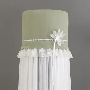 Close-up of the green cylindrical air conditioner cover with elegant white lace and floral decor.