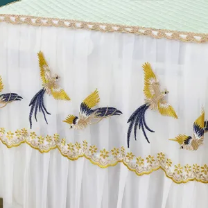 Dettaglio della copertura per lavatrice in stile nordico con pizzo bianco e ricamo dorato.