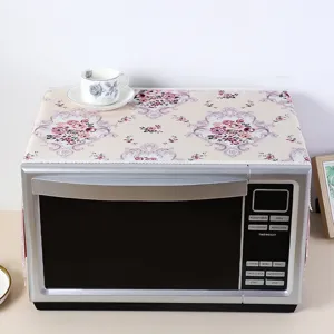 Detailed view of floral lace microwave oven dust cover set on kitchen appliance surface.