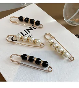 Primo piano di spille eleganti con perle e perline nere e distanziatori con strass luminosi.