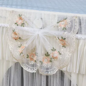 Primer plano de la funda para lavadora con elegantes volantes de encaje blanco y bordados florales.