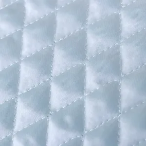 Detalle del tejido de la funda de lavadora con patrón acolchado de rombos y textura.