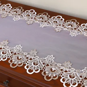 Elegante runner da tavola in pizzo bianco ricamato e dettaglio di copertura antipolvere raffinata.