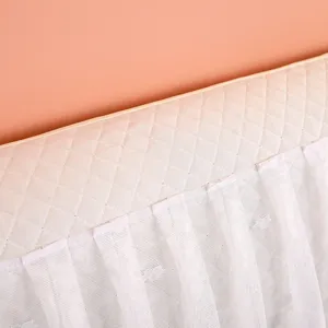 Close up view showing the delicate quilted texture and white lace trim of the soft headboard cover.