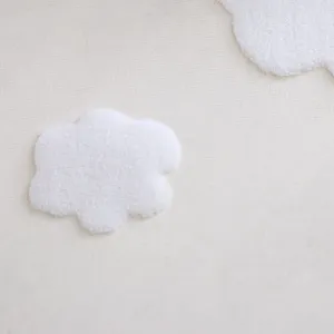 Detail shot of white mesh lace fabric featuring plush cloud appliqués, perfect for home decor.