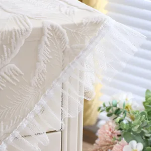 White lace bedside table cover detail view, showing delicate fabric texture and edge ruffle.