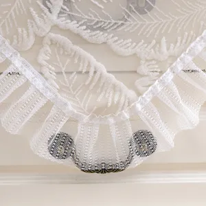 Close up of white lace dust cover detail, showcasing elegant embroidery and ruffles for home decor.
