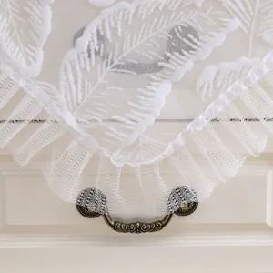 White lace dust cover detail showing delicate feather embroidery and lovely ruffled edges.