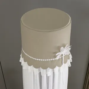 Detail view of the khaki cylindrical standing air conditioner cover with delicate white lace.