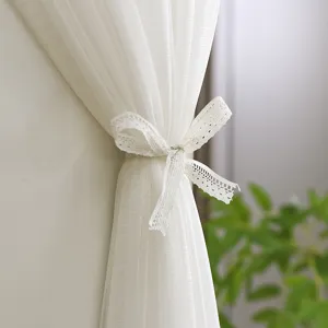 White lace sheer air conditioner cover detail, elegant bow tie design for home decor.