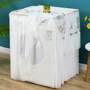 Copertura antipolvere per lavatrice in pizzo bianco con ricamo blu, dettaglio di arredamento.