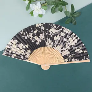 Detailed shot of traditional Japanese folding fan with black paper and floral pattern.