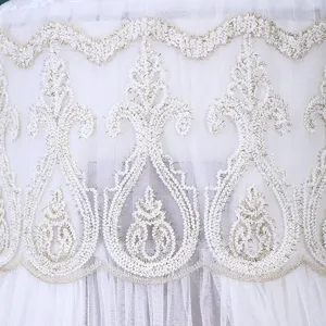 Primo piano dettagliato di tessuto in tulle bianco con elegante ricamo dorato per la casa.
