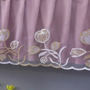 Close-up of pink dust cover with delicate tulip embroidery and scalloped hem for home decor.
