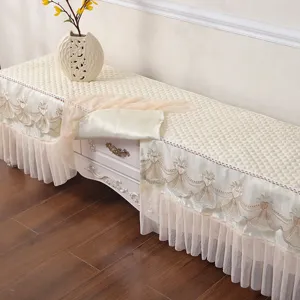 Elegante copertura antipolvere per mobile TV beige con delicate balze in pizzo e design trapuntato.