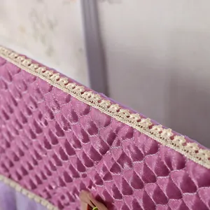 Primo piano della copertura antipolvere TV trapuntata viola con elegante bordo in pizzo.