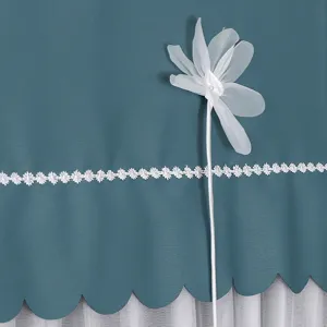 Nahaufnahme der Textil-Haubenschutzabdeckung mit weißer Spitzenborte und Blumendekor.