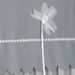 Nahaufnahme der grauen Stoff-Kühlschrankabdeckung mit weißer Spitzenborte und Chiffonblume.