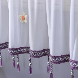 Vue détaillée du rideau de climatisation blanc diaphane avec dentelle et pompons.