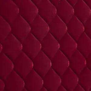 Primo piano dettagliato della texture della fodera per testiera in velluto trapuntato rosso scuro.