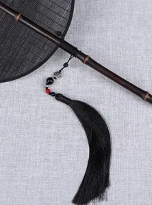 Primo piano del dettaglio del ventaglio in bambù cinese tradizionale con nappa nera e perline.