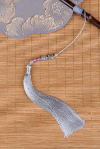 Λεπτομέρεια κεντημένης στρογγυλής βεγγάρας κινεζικού στιλ με λαβή από μπαμπού και φούντα.
