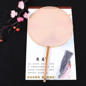 Detail shot of traditional Chinese round fan with wooden handle and elegant grey tassel.