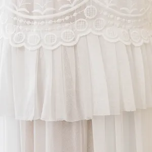Vista detallada del elegante bordado de encaje blanco y la tela de malla plisada de varias capas.