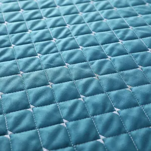 Primer plano detalle de tela acolchada con patrón de rombos turquesa para funda de lavadora.