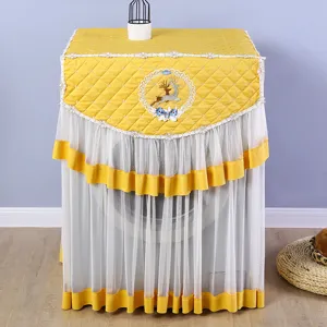 Vista detallada de funda acolchada amarilla para lavadora con elegante encaje y bordado de ciervo.