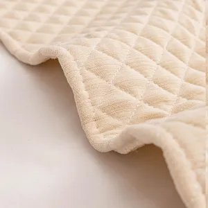 Close up of quilted fabric headboard cover, soft beige material with fine stitching detail.