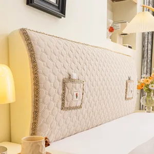 Close-up detail of quilted fabric headboard cover with elegant lace trim and convenient pockets.