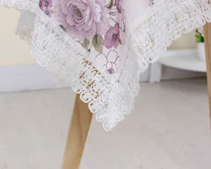 Close-up of elegant floral tablecloth edge with delicate white lace trim and purple flowers.
