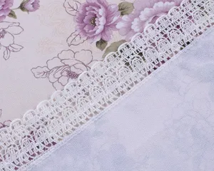 Close-up view of elegant floral tablecloth fabric with delicate white lace trim detail design.