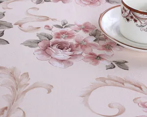 Close-up detail of vintage floral tablecloth, elegant pink fabric texture for home decor.