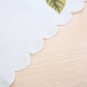 Close-up detail of white computer dust cover with scalloped edge and leaf pattern texture.